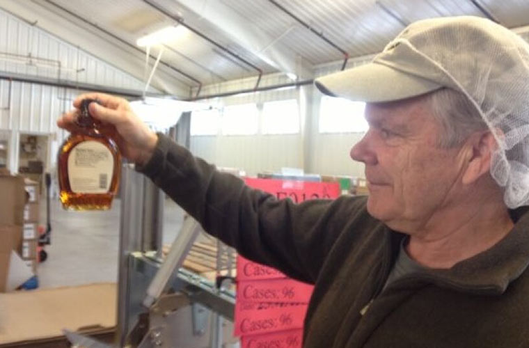 Photo of a man holding a bottle of maple syrup