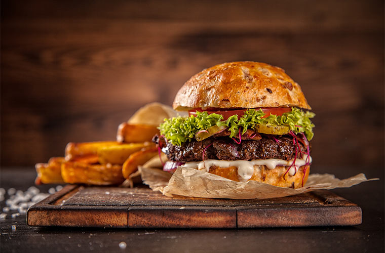 Photo of a hamburger and fries on a wooden cutting board