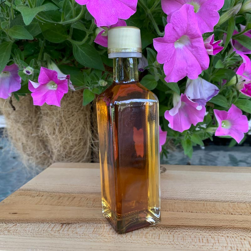 Photo of Marasca Square favor bottle with pink petunias in background