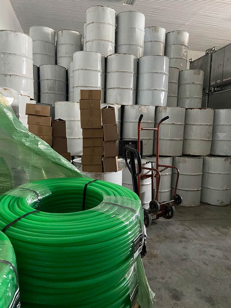A photo of white 55-gallon drums filled with Vermont maple syrup in a warehouse