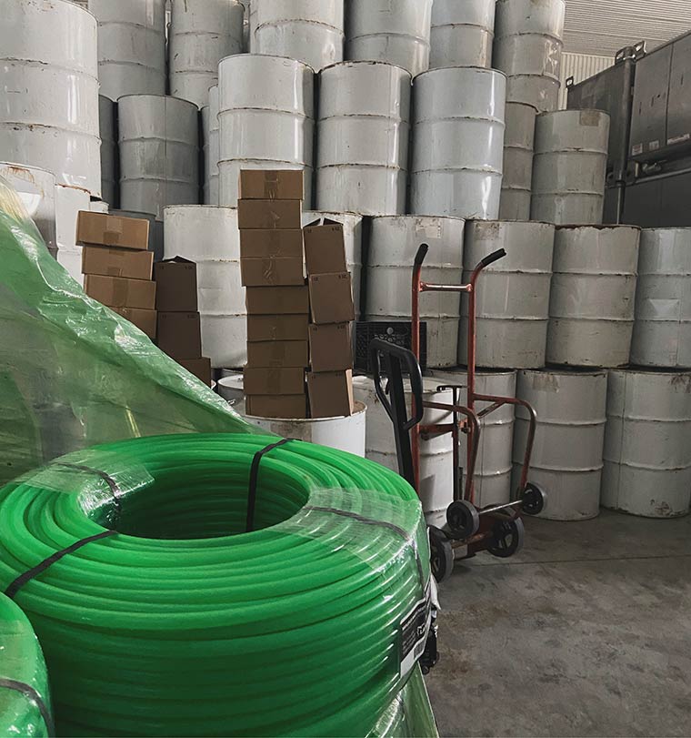 A photo of white 55-gallon drums filled with Vermont maple syrup in a warehouse